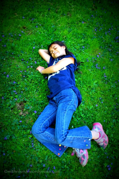 My 10 year old daughter resting on a carpet of grass and violets